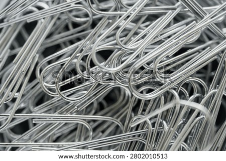 Closeup pile of silver paperclips, overlapping loops and cool metallic sheen, highdetail texture, stationery supply for organized workspace, monochrome tones with subtle