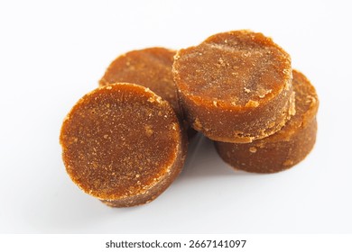 Closeup pile of solid, dark brown palm sugar discs (gula jawa or gula merah), a traditional sweetener used in a variety of desserts, beverages, and savory dishes.