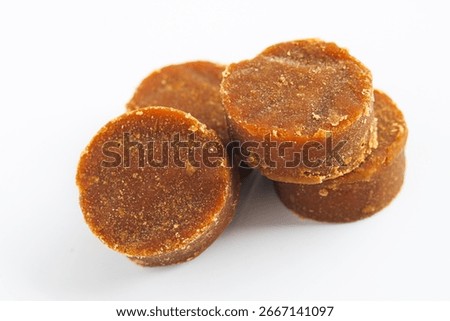 Closeup pile of solid, dark brown palm sugar discs (gula jawa or gula merah), a traditional sweetener used in a variety of desserts, beverages, and savory dishes.