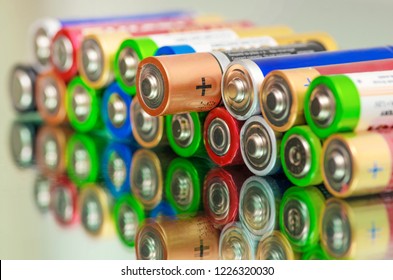 Closeup of pile of used alkaline batteries. Close up colorful rows of selection of AA batteries energy abstract background of colorful batteries. Alkaline battery aa size. Several batteries in rows.