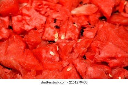 A closeup of a pile of watermelon fruit cuts into small pieces with seeds and without the green shell ready to be served as a healthy fresh snack, selective focus of a stack of  fresh ripe watermelon