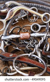 Close-up of a pile of well-used horse bits, tack leather and a rope (shallow depth of field).