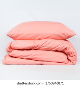 Closeup of pink folded blanket and pillow on white background.
