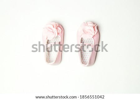 Close-up of pink sandals with a flower for a little girl. First shoes for baby girl on a light background with space for text. Top view. Baby shower party