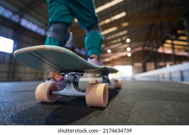 closeup pink skate wheel and foot or leg on back of child or kid girl playing skateboard or surfskate and start on indoor pump track in skatepark by extreme sports to wearing body safety knee support - Powered by Shutterstock
