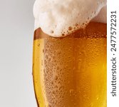 Close-up of pint glass filled with golden, amber beer topped with frothy white foam against grey studio background. Concept of food and drink, celebration, Oktoberfest, beverage industry. Ad