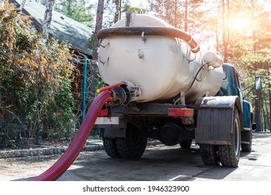 Close-up Pipe Hose Of Sewage Truck Car Engine Emptying Home Sewerage Tank. Septic Cleaning Vacuum Service And Maintenance Suburban Countryside Home. Suction Vehicle Cleaner Machine Pumping Drainage