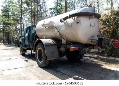 Close-up pipe hose of sewage truck car engine emptying home sewerage tank. Septic cleaning vacuum service and maintenance suburban countryside home. Suction vehicle cleaner machine pumping drainage