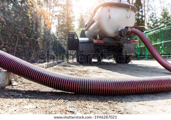 Close-up pipe hose of sewage truck car engine\
emptying home sewerage tank. Septic cleaning vacuum service and\
maintenance suburban countryside home. Suction vehicle cleaner\
machine pumping\
drainage
