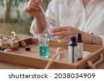 Close-up of a pipette with oil and a glass bottle. woman pouring perfume in bottle. Perfume creating workshop