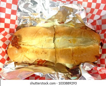 Closeup Of A Pizza Sub On Red And White Checkered Paper.