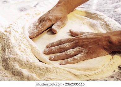 Close-up of pizzaiolo's hands stretching pizza dough on floured surface. Expert touch in traditional Italian pizza making art. - Powered by Shutterstock