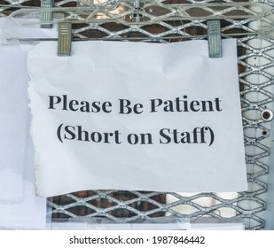 Closeup of plain printout hung outside a small retail business in Florida: "Please Be Patient (Short on Staff)" - Shutterstock ID 1987846442