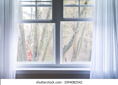 Closeup Of Plain White Window Curtains Blinds In Blue Room Interior Indoors With Wind Decoration, Outside Bare Tree In Winter