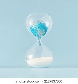 Close-up of planet Earth melting in hourglass on pastel blue background. Minimal creative concept of dystopian future. Anti-war idea, climate change or global pollution. The world provided by NASA.