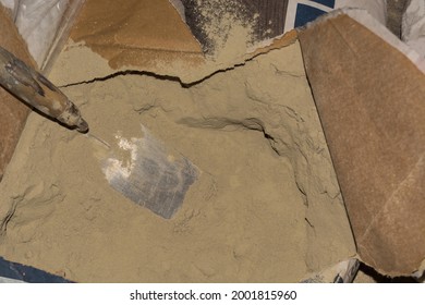 Close-up Of Plaster Trowel In Full Open Paper Bag Of Putty Powder For Wall Decoration,caulk Or Glaze.Concept Of Building Materials.Finish Coating In Dry Cement Powder Form.Selective Focus,copy Space
