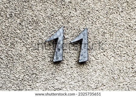 Close-up of a plastered wall with the number 11 on it.