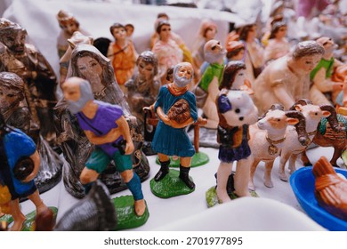 Close-up of plastic or ceramic figures of shepherds, sheep, and other Nativity characters displayed for sale at a traditional Christmas market.