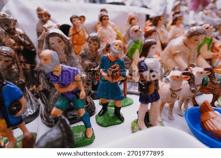 Close-up of plastic or ceramic figures of shepherds, sheep, and other Nativity characters displayed for sale at a traditional Christmas market.