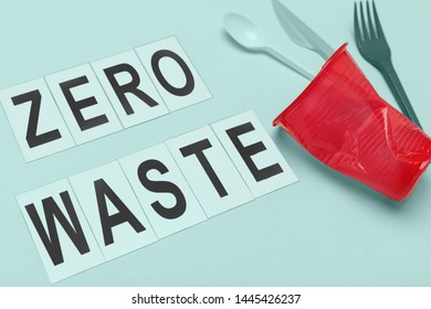 Closeup Plastic Cup And Utensils Placed Near Zero Waist Writing For Environmental Campaign Against Blue Background