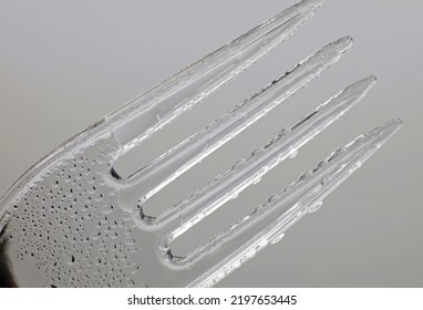 close-up plastic fork with water drops on a gray background
