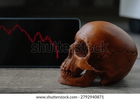 Close-up of a plastic human skull next to a smartphone displaying a sharp stock market crash. The screen shows red Japanese candlesticks plunging downward, symbolizing a financial meltdown. Perfect for trading, bear markets, economic crisis and investment risk themes