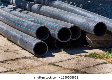 Close-up Plastic Main Black Pipes. 
A Heap Of Polyethylene Pipes For A Water Supply System. Objects For Laying Of City Communications And The Sewerage. Urban Scene