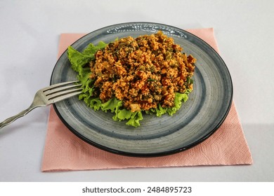 A close-up of a plate of bulgur salad with lettuce and tomatoes. The salad is served on a blue and gray plate and is garnished with fresh lettuce. - Powered by Shutterstock