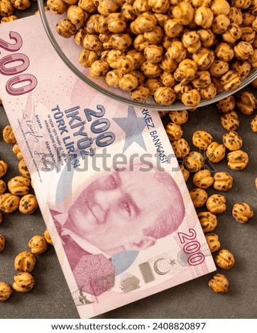 Close-up of a plate full of Turkish roasted chickpeas and 200 Turkish liras next to it, implying that the prices of roasted chickpeas are increasing.