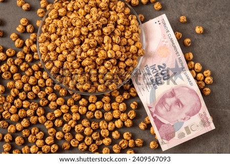 Close-up of a plate full of Turkish roasted chickpeas and 200 Turkish liras next to it, implying that the prices of roasted chickpeas are increasing.