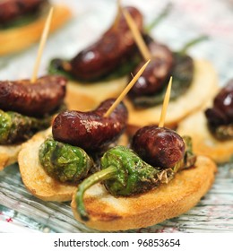 closeup of a plate with spanish pinchos made with chorizos an Padron peppers