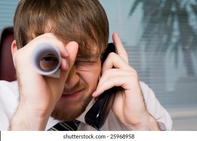 Close-up Of Playful Man With Paper Roll By His Eye While Speaking On The Phone