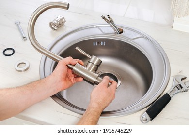 Close-up Plumber Hands Holds A New Faucet For Installing Into The Kitchen Sink, Plumbing Work Or Renovation