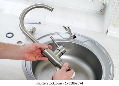 Close-up plumber hands holds a new faucet for installing into the kitchen sink, plumbing work or renovation - Shutterstock ID 1931869394