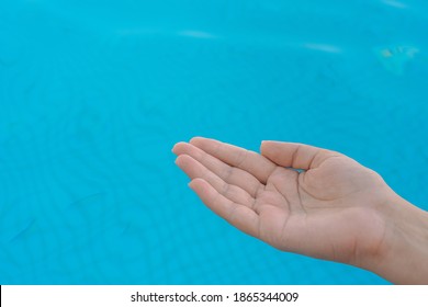 Closeup point of view image of one female opened cupped hand in gesture as if holding something virtual or invisible or asking something. Beautiful 1 female hand isolated on blue pool water background