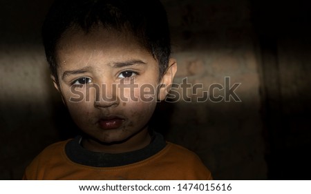 closeup of a poor staring hungry orphan boy in a refugee camp with sad expression on his face and his face and clothes are dirty and his eyes are full of pain