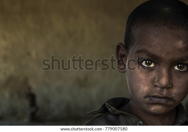 closeup of a poor staring hungry
orphan boy in a refugee camp with sad expression on his face and
his face and clothes are dirty and his eyes are full of
pain