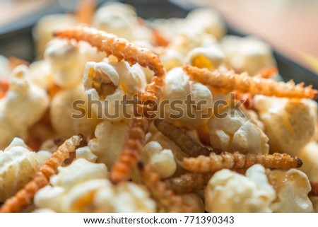 Closeup, Popcorn with bamboo worm fried insect on the black plate. Insect food is the healthy meal high protein diet concept, popular snack food in Thailand