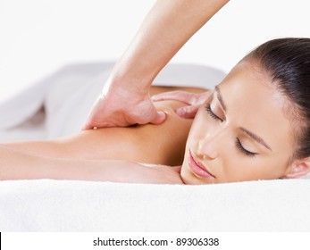 Close-up portait of relaxing woman having massage on her shoulder - white background