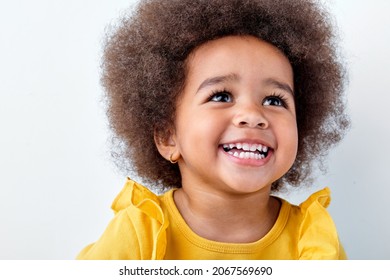 close-up portrait of an adorable, awesome black african girl laughing smiling isolated on white studio background, look up and laugh. copy space. children and people, people diversity concept