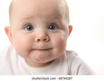 Closeup Portrait Of An Adorable Baby Sucking Lips With Blue Eyes