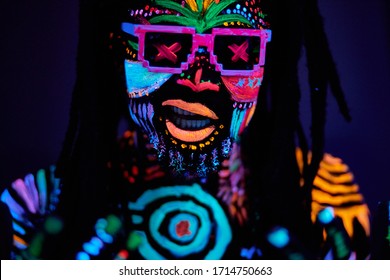 close-up portrait of african dj dancer with luminescent make-up and dreadlocks, wearing sunglasses. handsome guy isolated