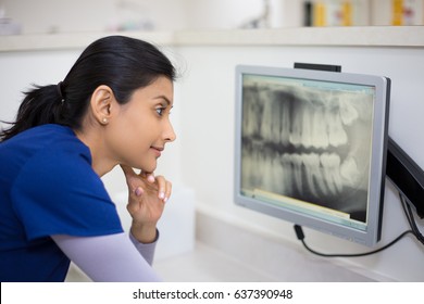 Closeup portrait of allied health dental professional in blue scrubs examining dental x-ray on computer screen, isolated dentist office - Shutterstock ID 637390948