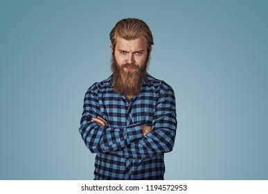 Closeup Portrait Of Angry, Mad, Pissed Off Handsome Man With Arms Crossed Folded. Hipster Male With Beard In Blue Plaid Checkered Shirt  Isolated On Blue Studio Background. Negative Face Expression.