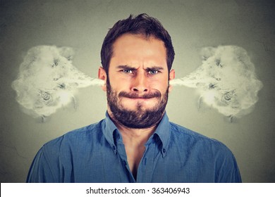 Closeup portrait of angry young man, blowing steam coming out of ears, about to have nervous atomic breakdown isolated gray background. Negative human emotions facial expression feelings attitude