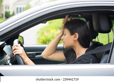 Closeup portrait, angry young sitting woman pissed off by drivers in front of her, hand on head, isolated city street background. Road rage traffic jam concept
