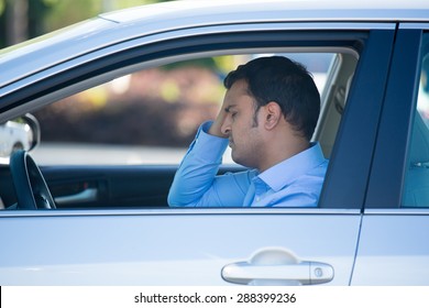 Closeup Portrait, Angry Young Sitting Man Pissed Off By Drivers In Front Of Him, Hand On Head, Isolated City Street Background. Road Rage Traffic Jam Concept