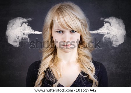 Closeup portrait of angry young woman, blowing steam coming out of ears, about to have nervous atomic breakdown, isolated black background. Negative human emotions facial expression feelings attitude