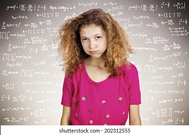 Closeup portrait annoyed, stressed, tired, young student standing in front of blackboard, fed up of studying, isolated chalkboard background filled with math, physics formulas. Face expression emotion