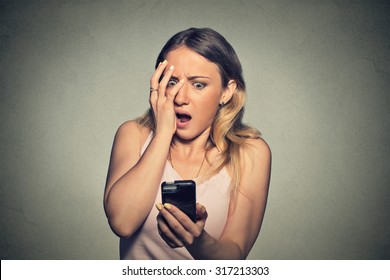 Closeup portrait anxious scared young girl looking at phone seeing bad news photos message with disgusting emotion on her face isolated on gray wall background. Human reaction, expression